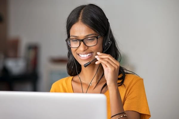 A smiling language professional with glasses working at a laptop